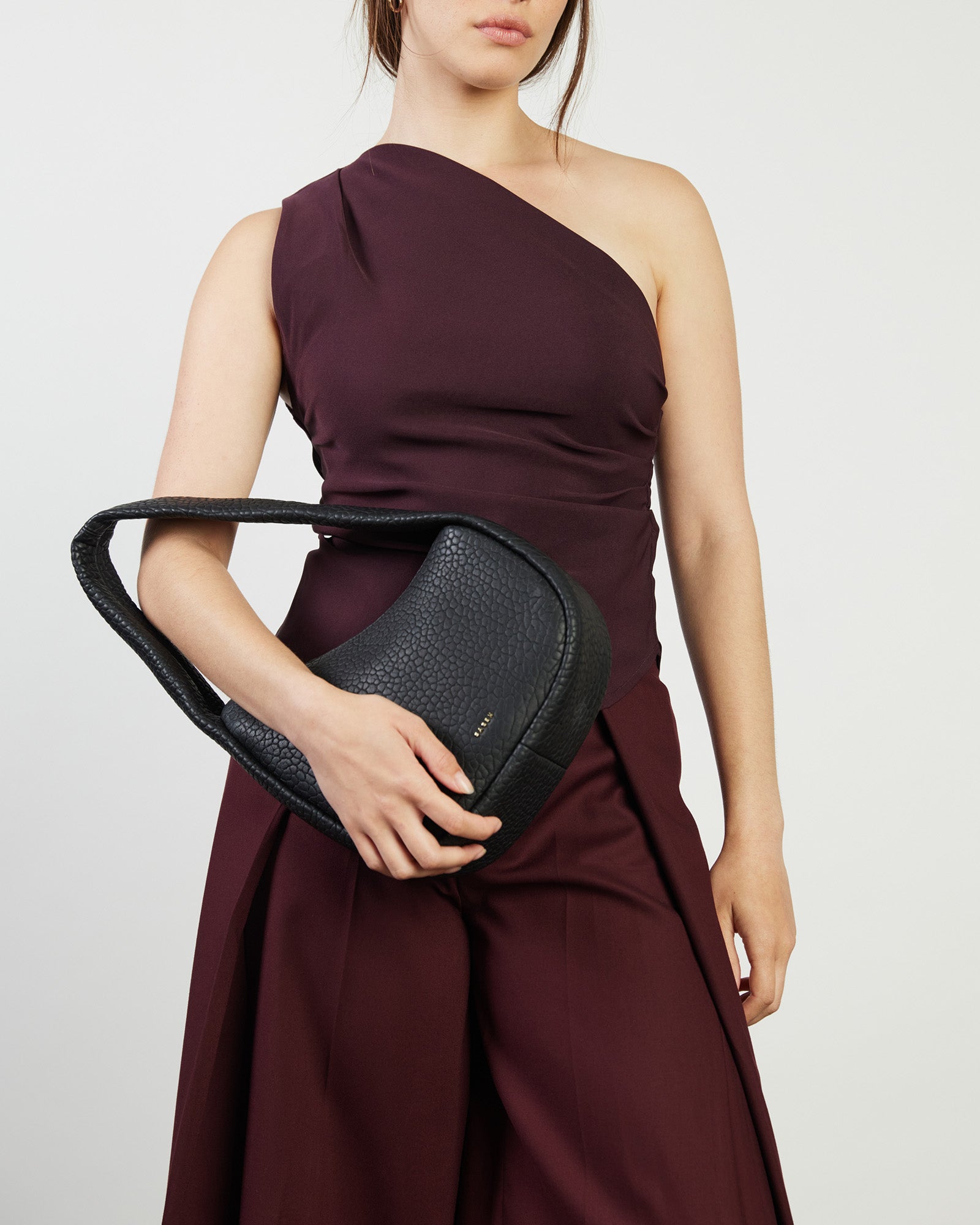 Black handbag with a textured surface on a white background