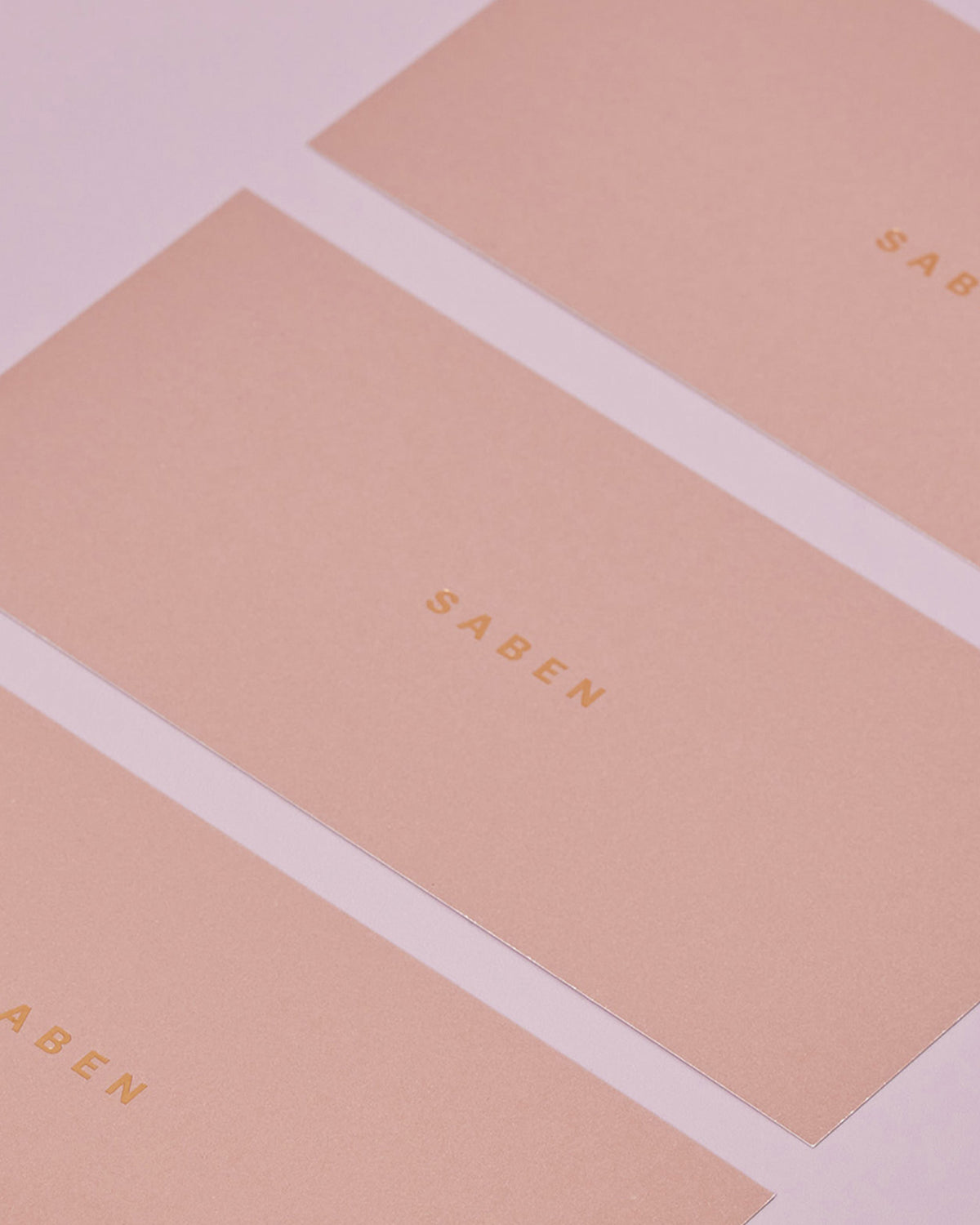 A collection of pink gift boxes with the Saben brand logo on them, stacked together.